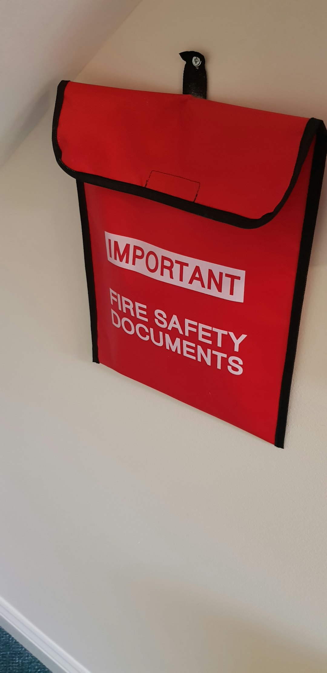 Photo by Alan Draper a red fire safety bag hanging on a wall