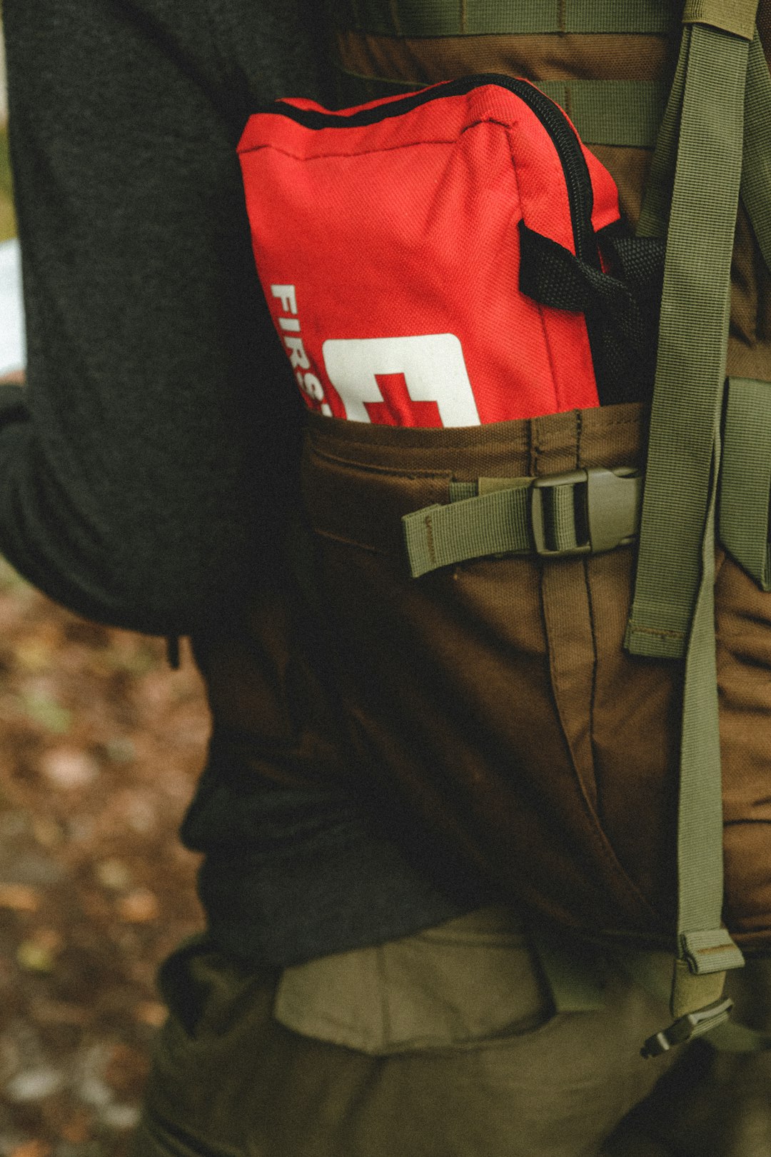 Photo by Mathias Reding man in red and black shirt and brown pants with black backpack